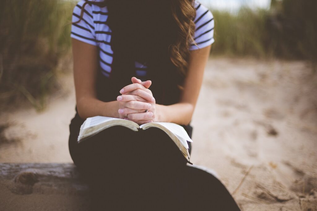 woman praying with a bible,scripturereel.com