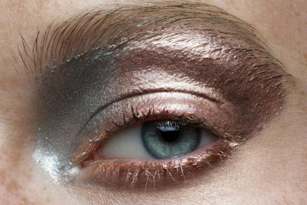 Extreme close-up of a person's eye with metallic eyeshadow and detailed skin texture.