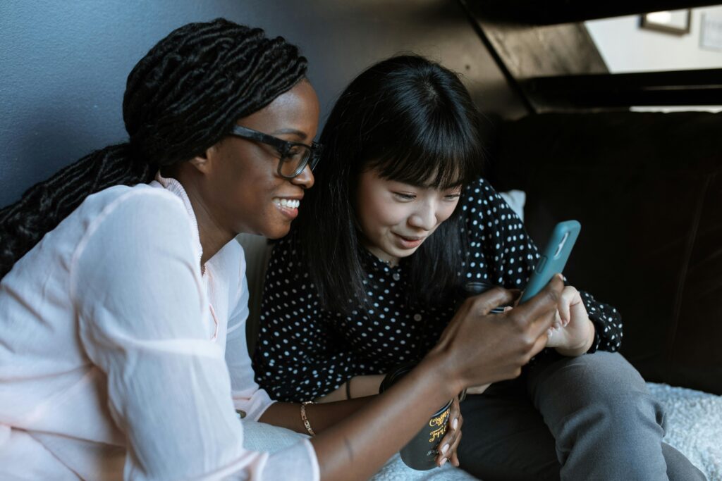 pexels-photo-5921981-5921981 Two women relaxed on a sofa, sharing and enjoying moments on a smartphone.